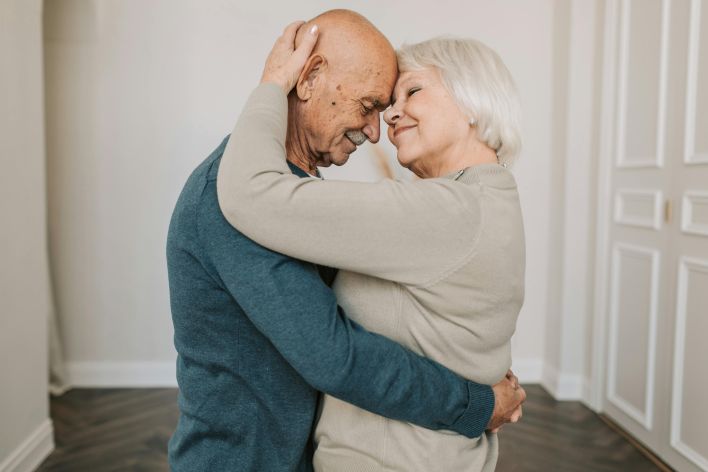 A joyful elderly couple embracing indoors, expressing love and happiness.
