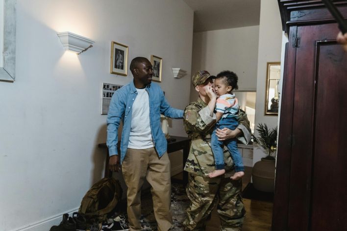 Emotional family reunion with a military mother, father, and child celebrating homecoming indoors.