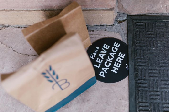 A package left on a doorstep with a sign reading 'Please Leave Package Here'. Ideal for delivery service concepts.
