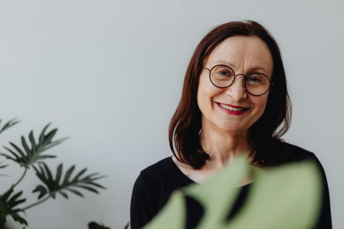 Portrait of a senior woman with eyeglasses, smiling warmly indoors.