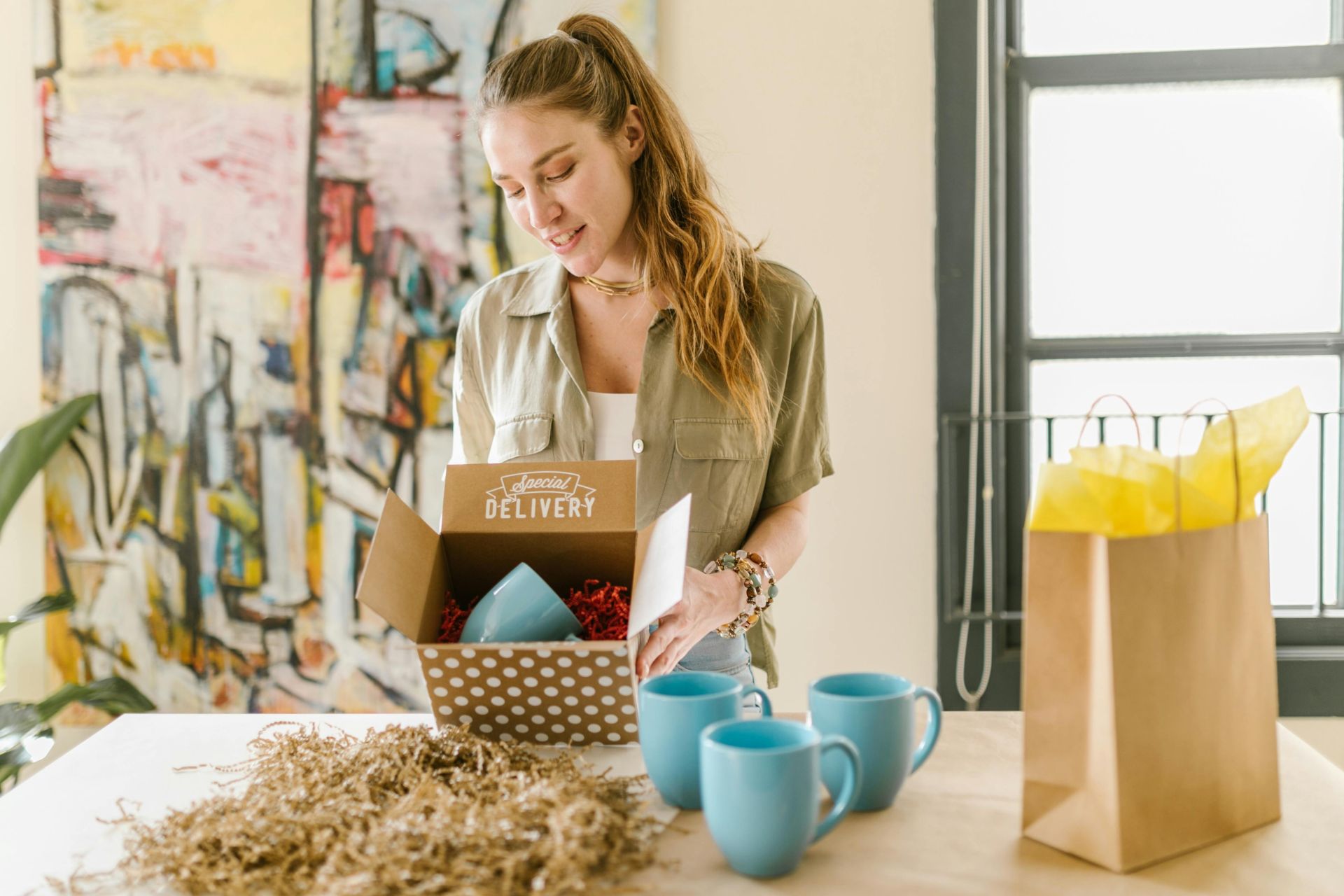 Concierge unpacking a special delivery box containing blue mugs in a cozy indoor setting.